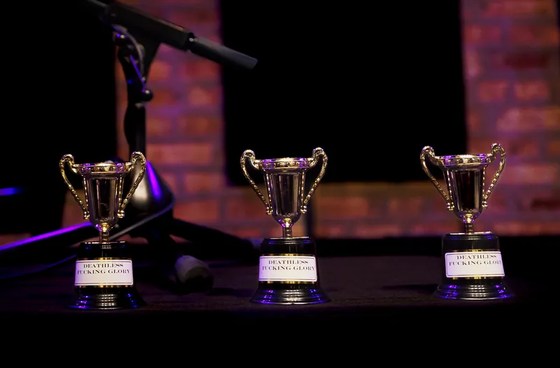 Three Loving Cup trophies lined up on the stage table