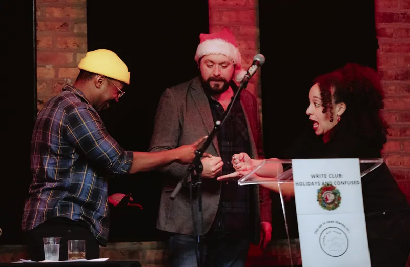 Three performers at the holiday show, one in a santa hat, mid-exchange