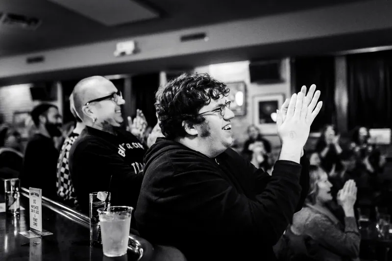 Two audience members applauding hard at the bar, in black and white