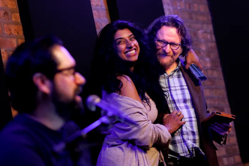 Three people laughing together on stage