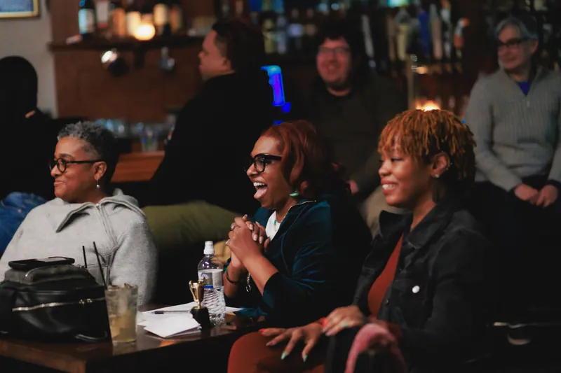 Three audience members laughing at their table