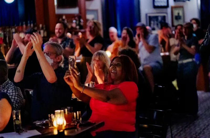 The crowd at candlelit tables, one person filming on a phone