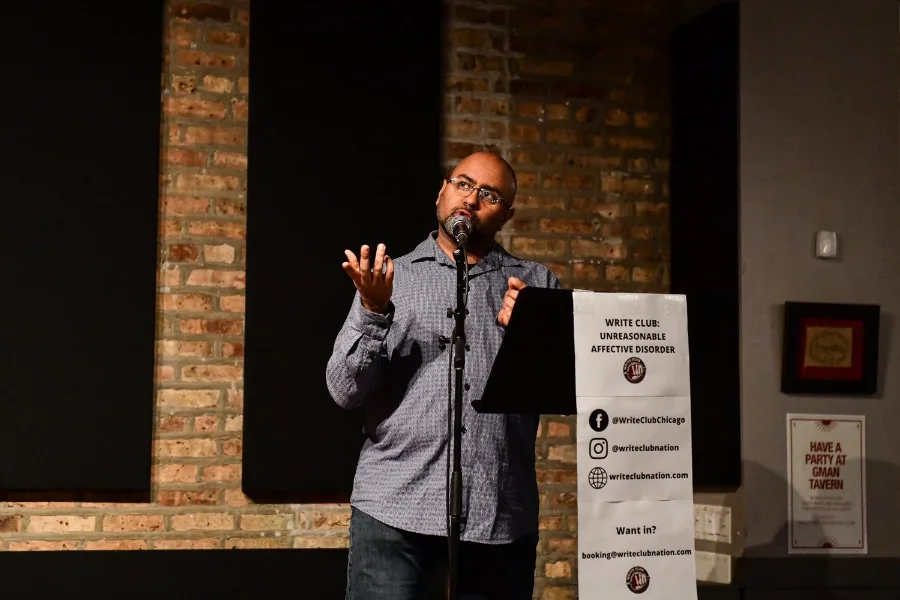 Bilal Dardai standing at the lectern, hands raised mid-essay
