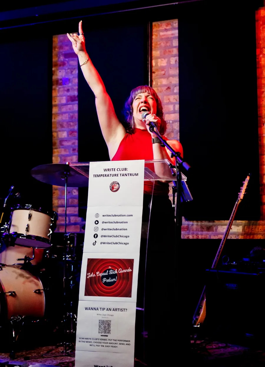 Corrbette Pasko at the lectern with one arm raised, mid-shout